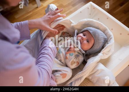 mettre des vêtements chauds sur bébé fille se préparant pour une marche le froid jour d'hiver. Banque D'Images