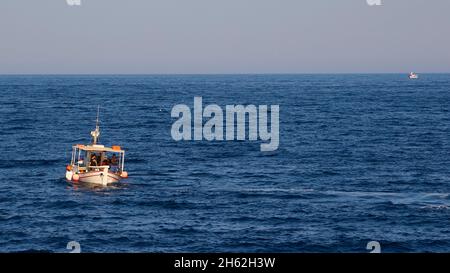 grèce,iles grecques,iles ioniennes,kefalonia,pessada,petit port de ferry,ferry pour zakynthos,tôt le matin,ferry 'agios gerasimos',lever du soleil,lumière du matin,petit bateau de pêche unique sur la mer,en arrière-plan un autre petit bateau Banque D'Images