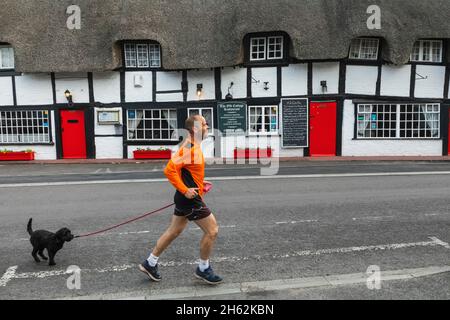 angleterre, hampshire, nouvelle forêt, ringwood, homme avec chien courant au-delà du xive siècle bâtiment à colombages de chaume maintenant l'ancien restaurant de cottage Banque D'Images