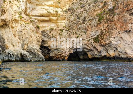 Bords rocailleux de la crique de iż-Żurrieq, près de la Grotte bleue, Malte, sortant de la mer Méditerranée et éclairé par le soleil du matin.Formations rocheuses avec Banque D'Images