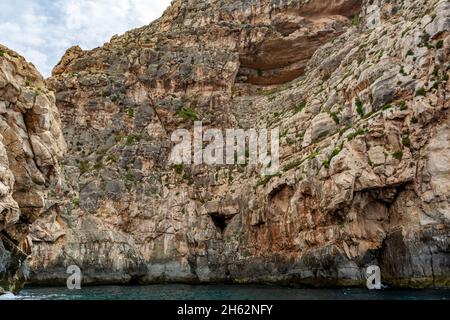 Bords rocailleux de la crique de iż-Żurrieq, près de la Grotte bleue, Malte, sortant de la mer Méditerranée et éclairé par le soleil du matin.Formations rocheuses avec Banque D'Images