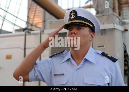 Reportage : le candidat Henry Ward, officier de la Garde côtière, salue l'abaissement de l'enseigne nationale le samedi 13 septembre 2014, à bord de l'aigle de la garde côtière, le grand navire américain, à Baltimore.Le voilier barque était dans l'arrière-port, participant au Star-Spangled Spectacular, un événement de plusieurs jours célébrant le 200e anniversaire de l'hymne national. Banque D'Images