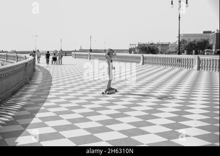 skater fille de patinage et de saut sur terrazza mascagni à livourne, en italie. son grand belvédère sinueux vers la mer avec une surface pavée de 8700 m² comme un damier et 4,100 balusters Banque D'Images