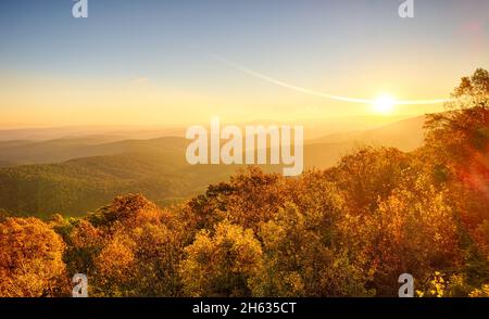 Lever du soleil en novembre sur le sommet de montagne scéninc dans la forêt nationale d'Ouachita, avec des couleurs d'automne, de la brume lourde et du brouillard dans les vallées, et des éruptions solaires Banque D'Images