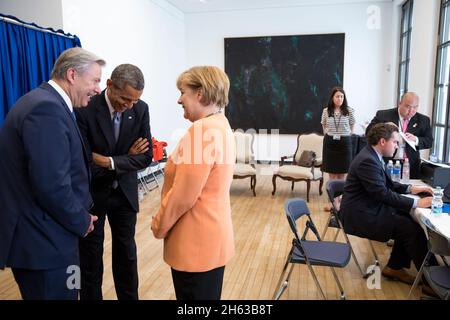 Le président Barack Obama s'entretient avec la chancelière Angela Merkel et le maire de Berlin Klaus Wowereit avant de faire une déclaration à la porte de Brandebourg à Berlin, en Allemagne, le 19 juin 2013. En arrière-plan, de gauche à droite, sont : Caitlin Hayden, directeur principal des communications stratégiques et porte-parole du SNRS; Cody Keenan, directeur de Speechwriting; et Gary Lee, associé Advance. Banque D'Images