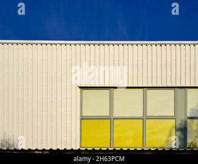 entrepôt blanc avec fenêtres jaunes, ciel bleu, Banque D'Images