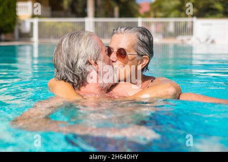 couple de deux aînés heureux s'amuser et s'amuser ensemble dans la piscine souriant et jouant. les gens heureux appréciant l'été dehors dans l'eau Banque D'Images