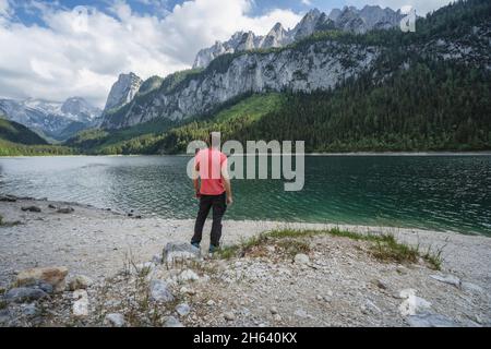 homme appréciant les montagnes de dachstein se reflète dans le lac de gosau, autriche. Banque D'Images