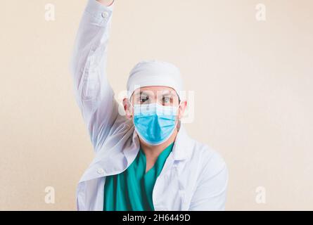 Un médecin choqué dans un masque médical de protection et un manteau de laboratoire blanc avec handup fermé isolé Banque D'Images