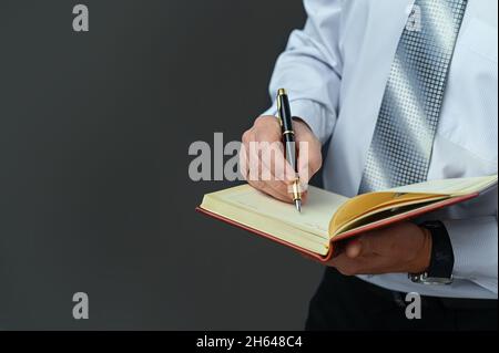 Homme d'affaires fait des notes dans un bloc-notes avec un stylo plume. Maquette Banque D'Images