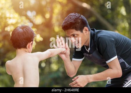 Boxe pour enfants. Boxeur pour jeunes garçons pratique les coups muay Thai avec entraîneur de père. Banque D'Images