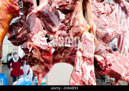 Des morceaux de viande hachés sur des os sont suspendus pour être vendus sur le marché Altyn Orda, le plus grand marché d'Almaty, au Kazakhstan Banque D'Images