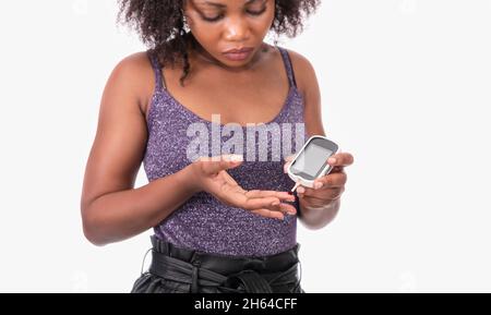 Femme utilisant un glucomètre numérique sur fond blanc Banque D'Images