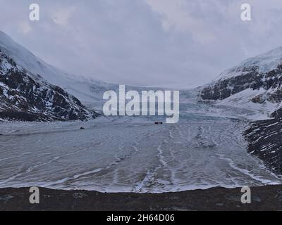 Vue sur le majestueux glacier Athabasca dans le parc national Jasper, en Alberta, au Canada, qui fait partie du champ de glace Columbia dans les montagnes Rocheuses, avec un énorme autobus. Banque D'Images