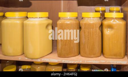 Miel naturel dans divers bocaux sur une étagère en bois, marché souvenir du village. Banque D'Images