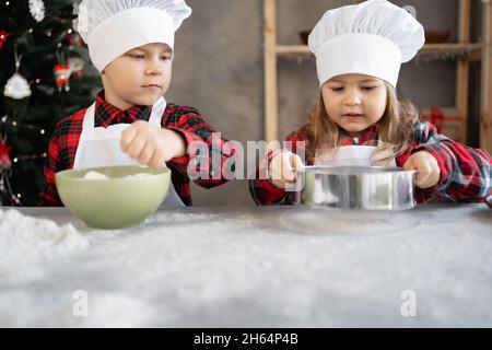 Gros plan boulanger frère et soeur dans la cuisine préparant des biscuits de Noël.Processus de fabrication de pain d'épice de Noël.Les enfants font de la pâte pour la cuisson. Banque D'Images