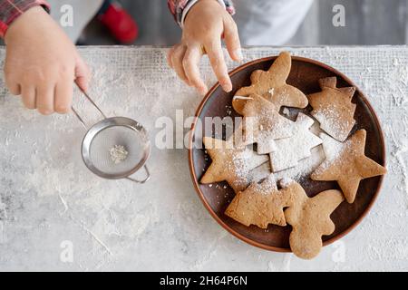 Décoration de Noël biscuits de pain d'épice avec sucre en poudre.Biscuits en forme d'étoile, homme et chevrons sur une assiette dans la cuisine. Banque D'Images