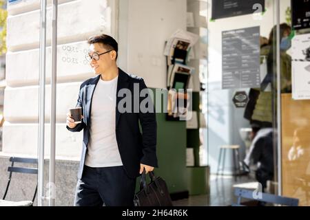 Homme avec un café venant de l'entrée du bâtiment Banque D'Images