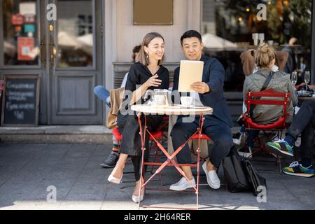 Personnes ayant des appels vidéo sur tablette numérique au café Banque D'Images