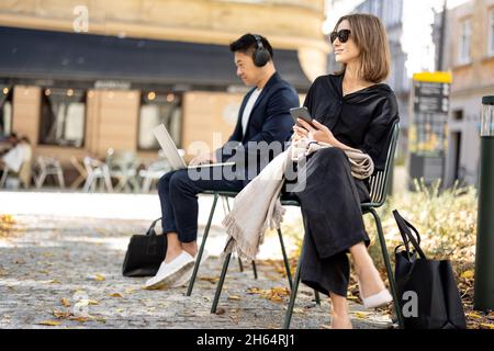 Homme d'affaires travaille sur un ordinateur portable et femme va en ville Banque D'Images