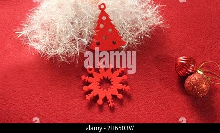 Décoration de Noël : décorations de Noël rouges en feutre sous la forme d'un sapin de Noël, flocons de neige sur fond rouge et blanc brillant Banque D'Images