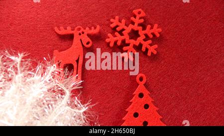 Décoration de Noël : décorations de Noël rouges en feutre sous forme d'arbre de Noël, de cerf et de flocons de neige sur fond rouge et blanc Banque D'Images