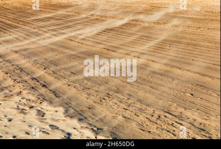 Fond de sable, vagues de sable le jour venteux sur la plage ou dans le désert, fond naturel.Vent fort sur la plage, tempête de sable.Le sable vole dans le f Banque D'Images
