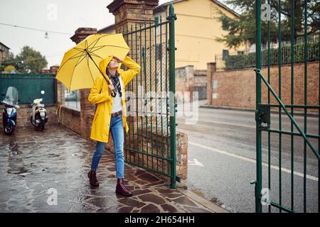 Une jeune fille avec un imperméable jaune et un parapluie sort pour une promenade dans une atmosphère paisible sur la pluie.Promenade, pluie, ville Banque D'Images