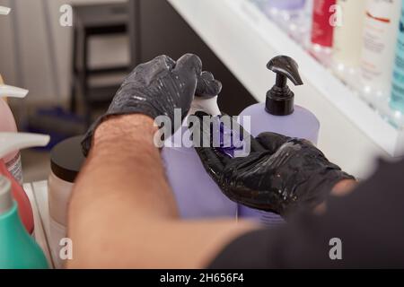 Le coiffeur tire le shampooing blond violet de la bouteille Banque D'Images