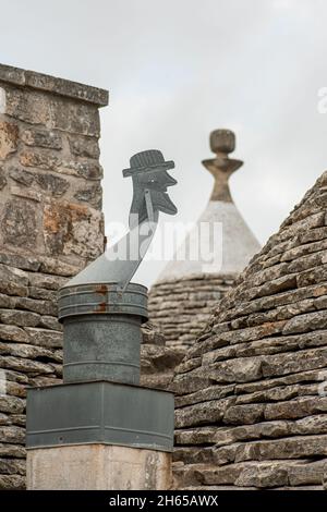 Ancien toit Trullo avec une girouette artisanale typique dans la campagne, ancienne maison traditionnelle et vieux mur en pierre à Puglia, Italie, Europe, vertical Banque D'Images