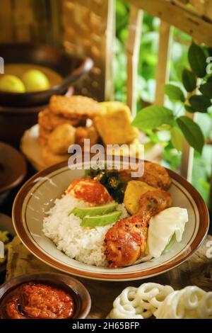 Nasi Campur. Repas indonésien de riz avec une variété de plats d'accompagnement, servi dans un style modeste Banque D'Images