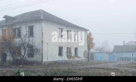 Une maison en bois abandonnée de deux étages au bord de la route par un jour brumeux Banque D'Images