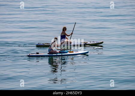 Deux femelles paddleboard sur un très calme, chaud jour de juillet, près de Charlestown, sud de Cornwall, Royaume-Uni. Banque D'Images