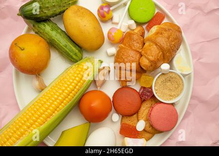 Aliments malsains sur fond coloré, vue du dessus.Croissant français, bonbons sur bâton, bonbons, guimauves, biscuits et macarons sur BRI jaune Banque D'Images