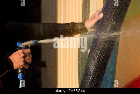 l'homme nettoie les équipements de sport à wingfoil, avec un tuyau d'eau sous pression Banque D'Images