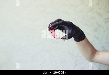 un maître d'épilation en gants noirs tient une pâte d'épilation à sucre rose dans ses mains. gros plan. Banque D'Images