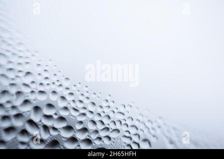 L'eau tombe sur fond blanc texture. Toile de fond verre recouvert de gouttes d'eau. Bulles dans l'eau.Cellules, gouttes d'eau sur verre, macro gros plan Banque D'Images