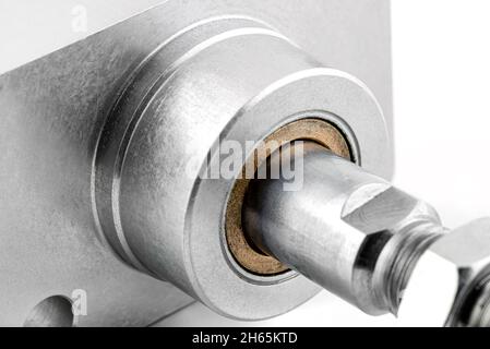 Photo macro d'un joint de piston en cuivre provenant d'un cylindre pneumatique avec un filetage et un écrou à l'extrémité, isolé sur un fond blanc. Banque D'Images