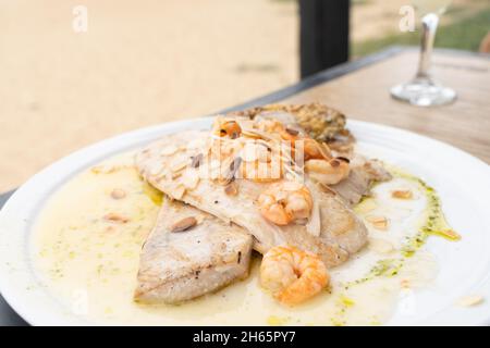 Steak de poisson grillé avec crevettes et amandes sur l'huile.Assiette de menu de restaurant, concepts de plats principaux Banque D'Images