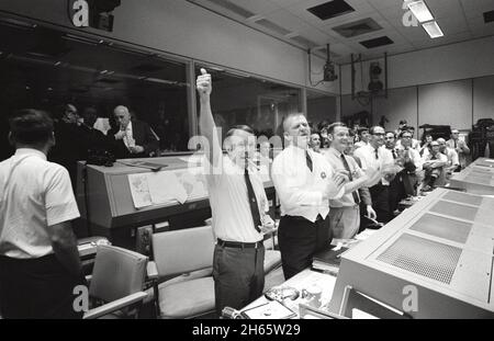 Trois des quatre directeurs de vol Apollo 13 applaudissent le succès de l'échec du module de commande « Odyssey », tandis que le Dr Robert R. Gilruth, directeur du Centre spatial habité (SMC), et le Dr Christopher C. Kraft Jr., directeur adjoint du SMC, éclairs les cigares (en haut à gauche).Les directeurs de vol sont de gauche à droite : Gerald D. Griffin, Eugene F. Kranz et Glynn S. Lunney. Banque D'Images