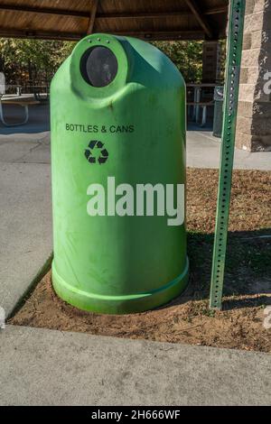 Un bac de couleur verte séparé pour l'écologie des bouteilles et des canettes recyclables portant un symbole de recyclage devant le pavillon de pique-nique du parc Banque D'Images