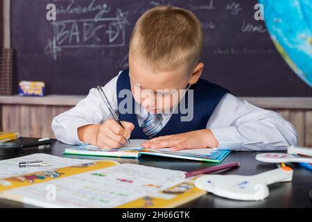 Jeune Ecolier Assis A Ecrire Des Notes A L Ecole Assis A Son Bureau Dans La Salle De Classe Photo Stock Alamy