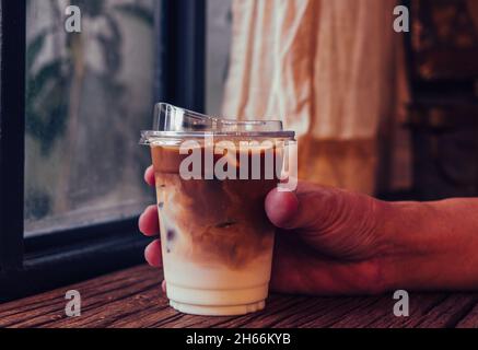 Tenez le café latte glacé à la main dans un grand verre. Arrière-plan de boisson d'été froide Banque D'Images