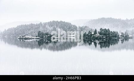 Paysage marin d'hiver , réflexions .Petites îles en pierre cultivées avec des arbres dans l'eau fixe.Arrière-plan flou, brumeux.neige, pluie, mauvais temps. Banque D'Images