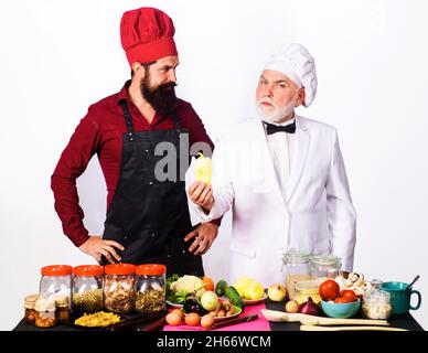 Deux chefs en uniforme se trouvent près de la table avec des légumes.Chef avec assistant dans la cuisine prêt à cuisiner.Cuisine professionnelle.Une alimentation saine Banque D'Images