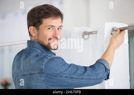 mâle d'installation d'un rideau Banque D'Images