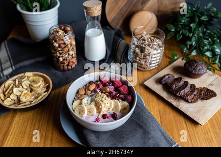 Un bol de petit déjeuner sain avec du lait, des bananes, des noix, des baies et du granola Banque D'Images