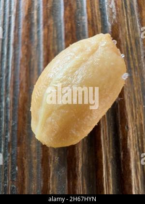 Gros plan de cacahuètes frites pelées et salées sur une planche de bois Banque D'Images