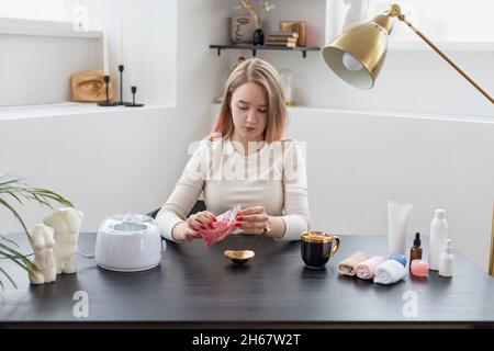 Jeune femme qui fait de la cire, l'enlèvement de cheveux, le sharing.Petite entreprise, procédure d'enseignement de concept. Banque D'Images