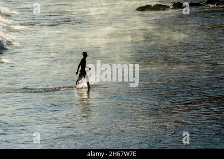 Homme sortant lentement de la mer de la plage d'Ondina après avoir été baigné.Salvador Bahia Brésil. Banque D'Images